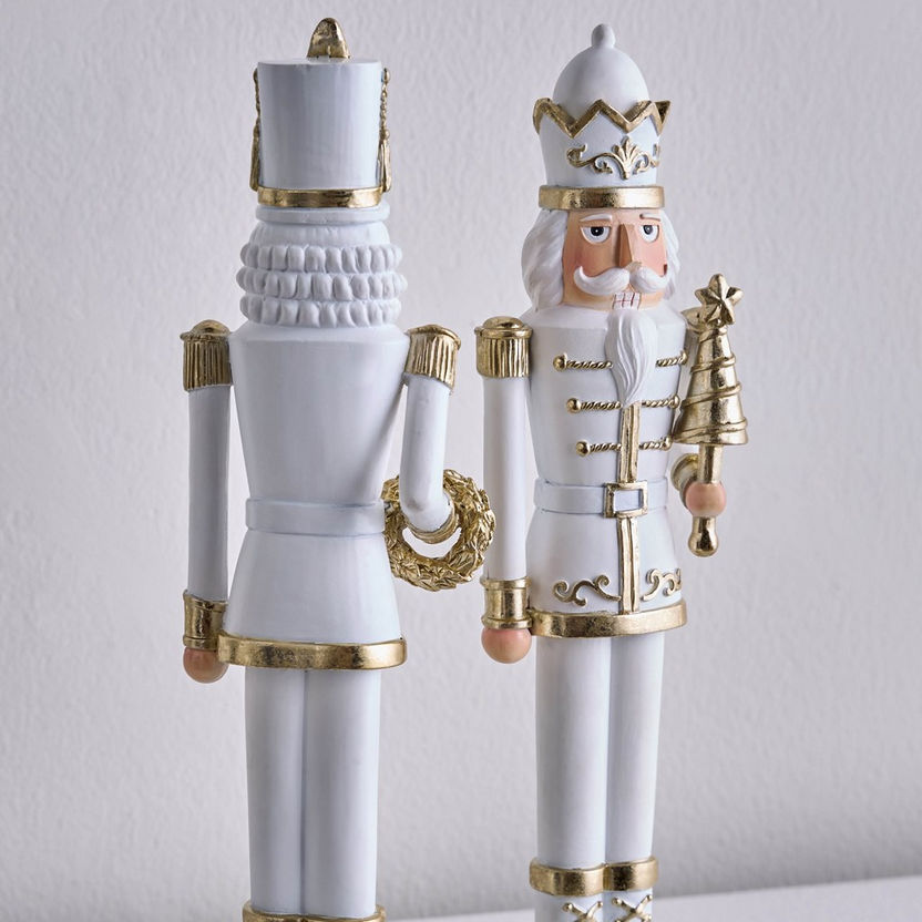 Decorative nutcrackers with white and gold attire on a light gray background