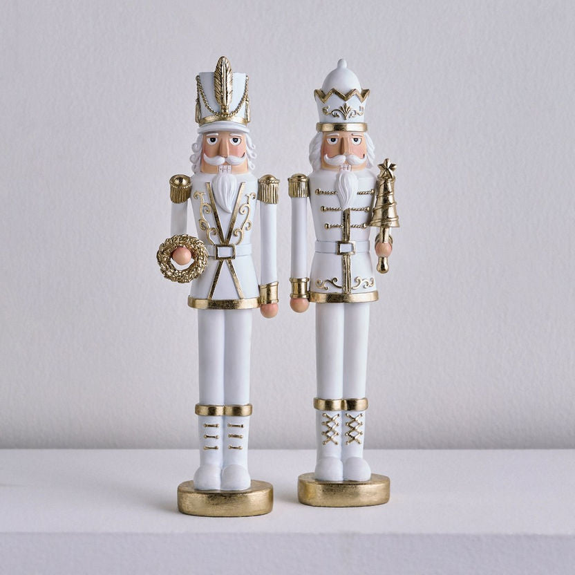 Two decorative nutcrackers with white and gold attire on a light gray background