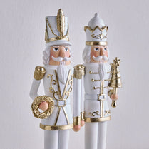 Two decorative nutcrackers with gold and white attire on a light gray background