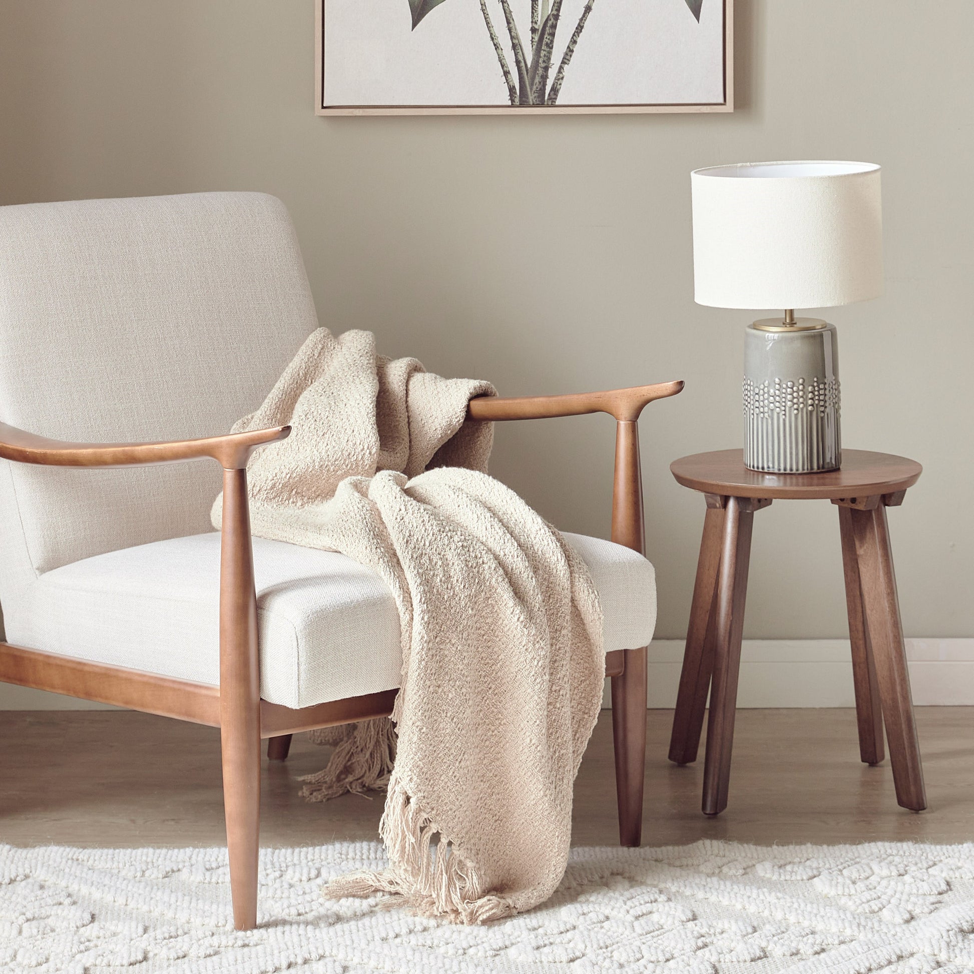 Cozy living room with a wooden armchair, beige blanket, and a side table with a lamp.