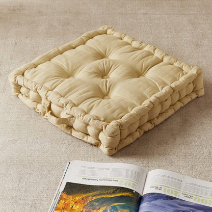 Beige cushion on a textured surface with an open magazine underneath