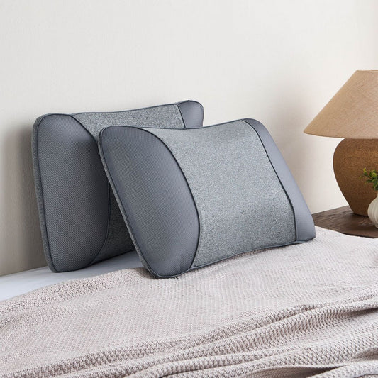 Gray memory foam pillows on a bed with a lamp in the background