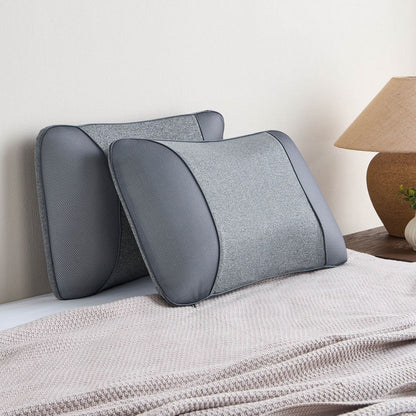 Gray memory foam pillows on a bed with a lamp in the background