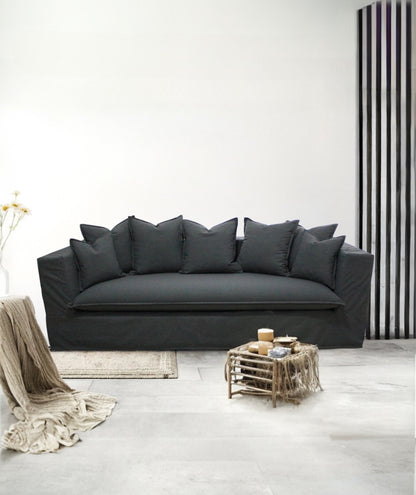 Gray sofa in a minimalistic living room with a striped wall. Paris Collection Sofa – Classic Elegance Reimagined | Vella Concept