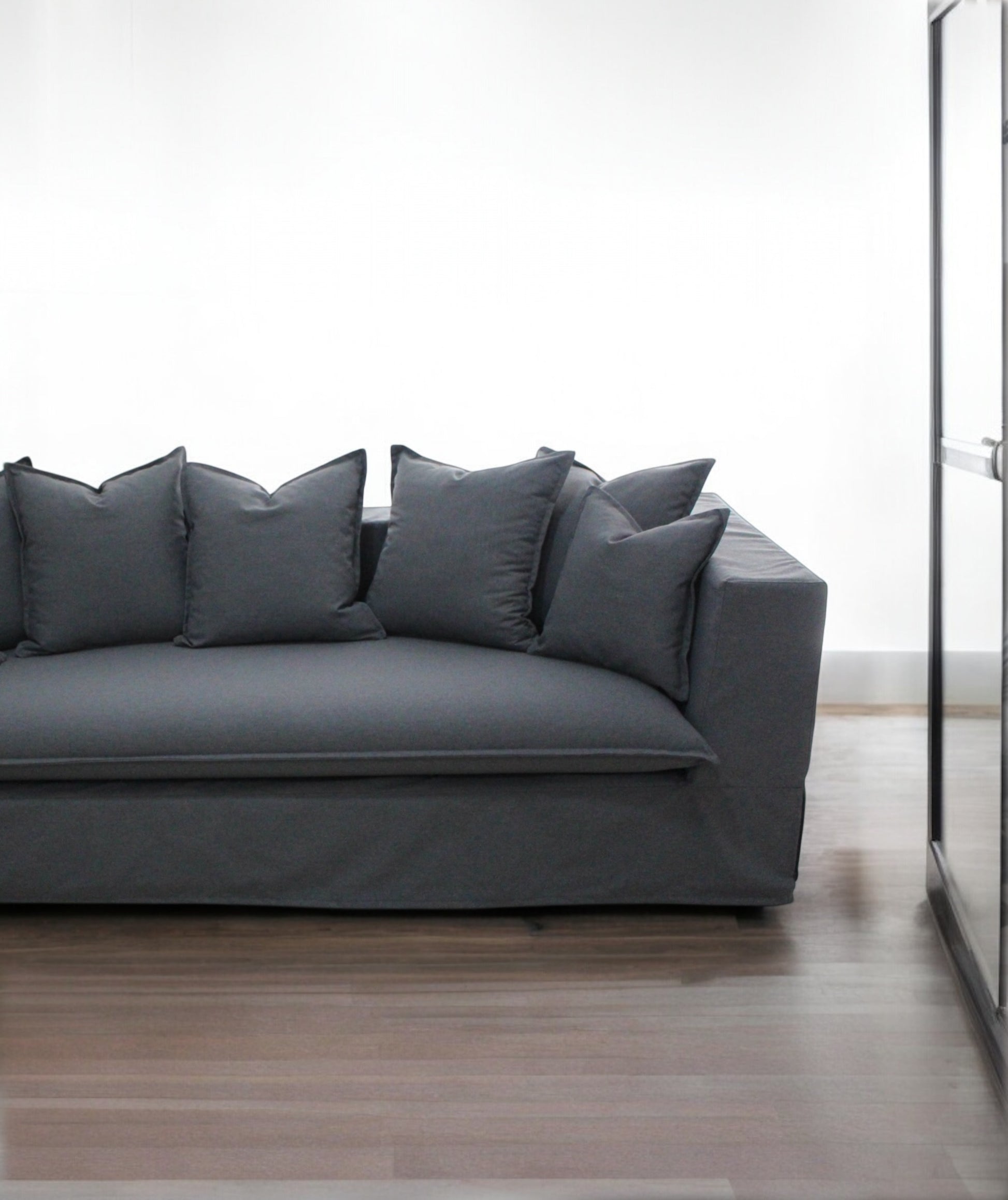 Gray sofa with decorative pillows in a minimalistic room. Paris Collection Sofa – Classic Elegance Reimagined | Vella Concept