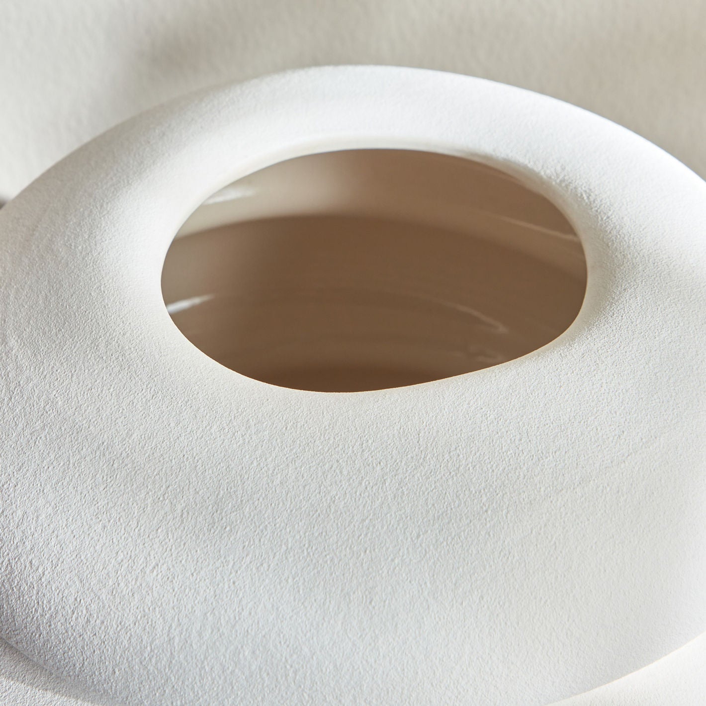 Close-up of a white toilet seat with a brown rim on a beige background