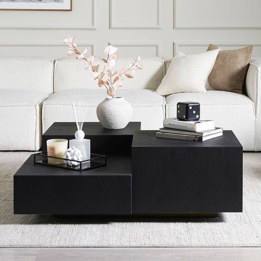 Modern living room with a black coffee table, white sofa, and decorative items.