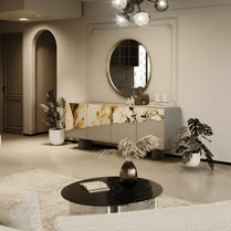 Modern living room with a round mirror, decorative table, and plants.