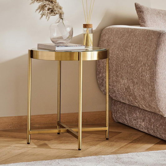 Gold side table with decorative items next to a brown sofa in a living room setting.