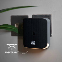 Dr. Scent night light device attached to a wall socket with a plant in the background.