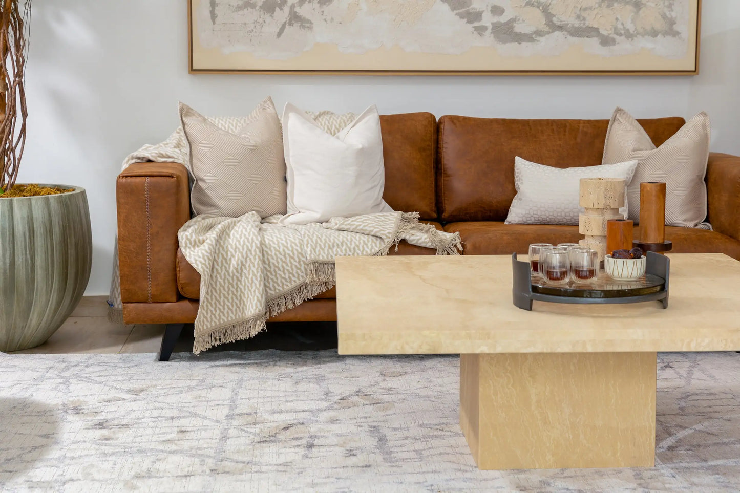 Living room with brown leather sofa, wooden coffee table, and decorative items.