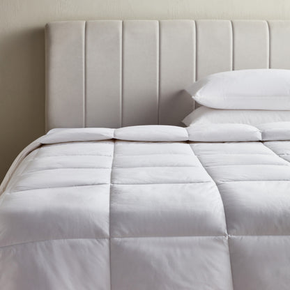 White comforter on a bed with a tufted headboard
