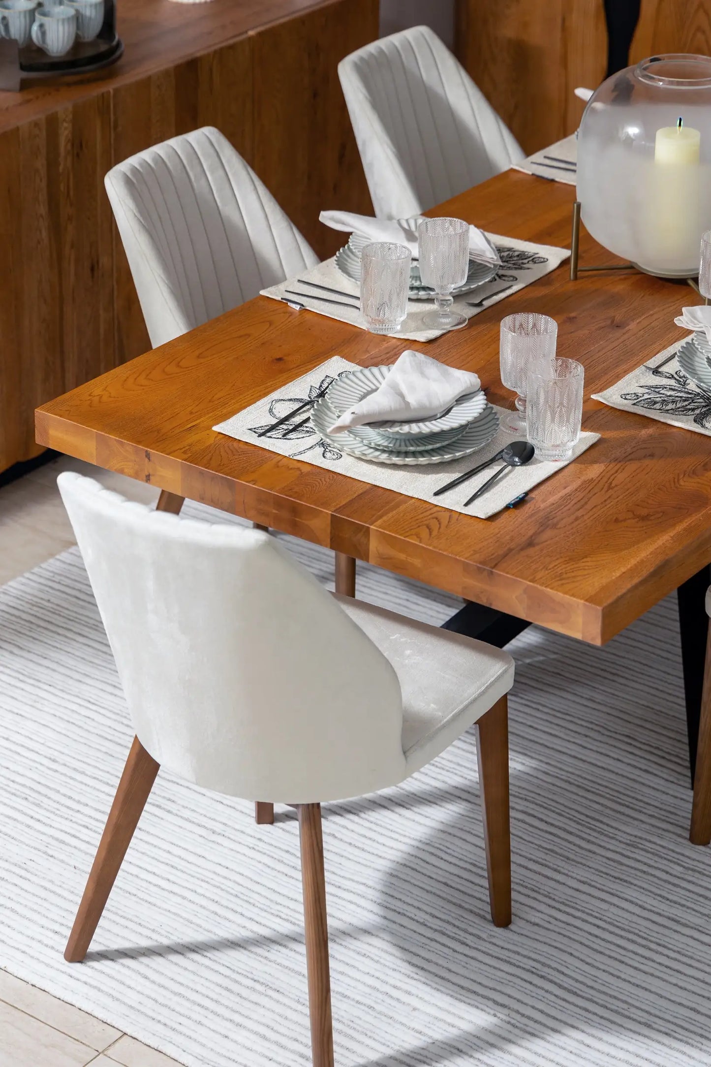 Dining table set with plates, glasses, and cutlery in a modern kitchen.
