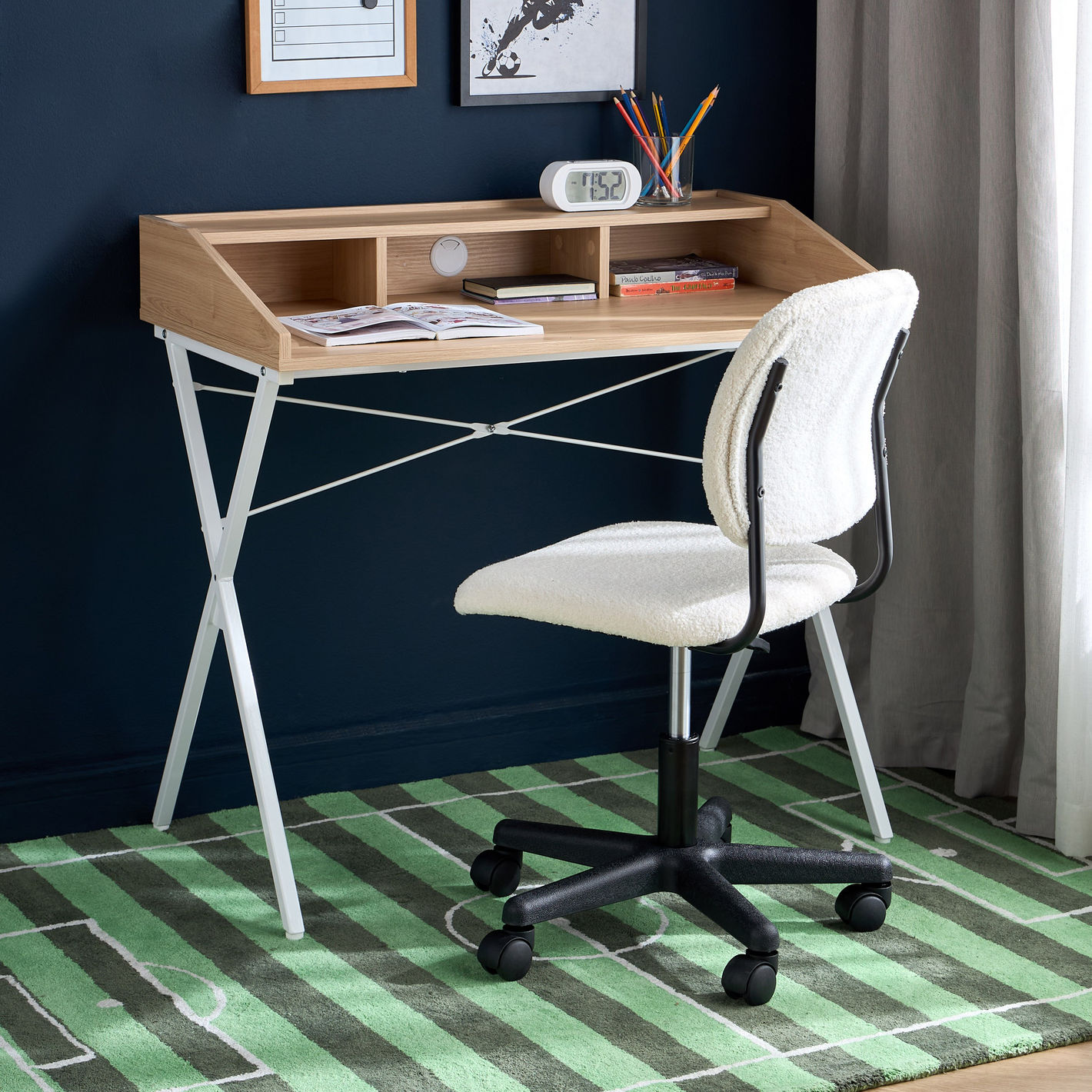 Wooden desk with white chair against a dark blue wall with a green and white checkered floor.