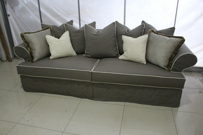 Gray sectional sofa with decorative pillows on a tiled floor. Roma Collection Sofa – Serene Comfort in a Chaotic World | Vella Concept