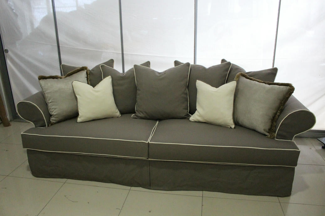Gray sofa with decorative pillows against a white wall. Roma Collection Sofa – Serene Comfort in a Chaotic World | Vella Concept