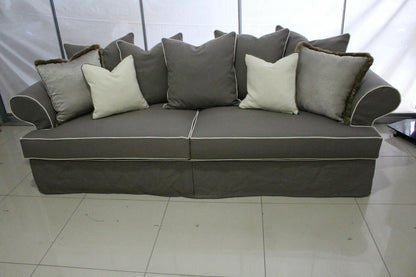 Gray sofa with decorative pillows on a tiled floor. Roma Collection Sofa – Serene Comfort in a Chaotic World | Vella Concept