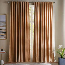 Brown curtains hanging in a room with a small table and plant.