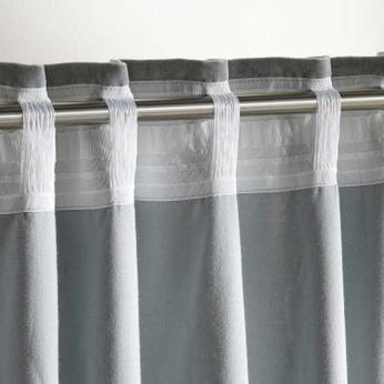 Gray curtain with white sheer overlay on a rod against a light background