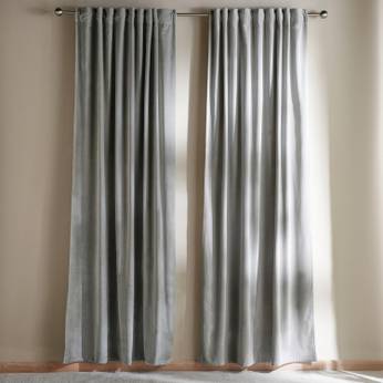 Pair of gray curtains hanging on a rod against a beige wall.
