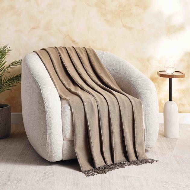 Beige blanket draped over a white armchair in a cozy living room setting.