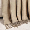 Beige blanket with fringes on a soft surface