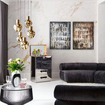 Modern living room with black sofa, glass coffee table, and gold pendant lights.