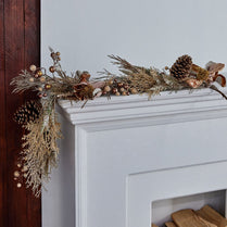 Decorative garland with pinecones and flowers on a fireplace mantel.