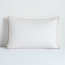 White pillow with a gold trim on a white background