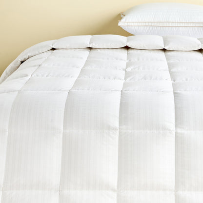 White comforter on a bed with pillows against a beige wall