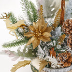 Decorative arrangement with gold poinsettia, pine branches, cinnamon sticks, and pinecones on a white background.