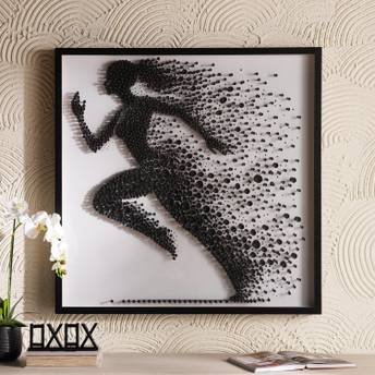 Framed artwork of a running person made from black dots on a textured wall.
