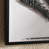 Close-up of a black framed mirror with decorative elements on a textured surface