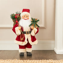 Decorative Santa Claus figure holding a gift and a basket of toys on a neutral background