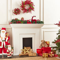 Christmas decorations including wreaths, Santa figurines, and presents around a fireplace.