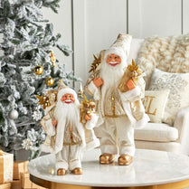 Decorative Santa figurines on a table with a Christmas tree and sofa in the background