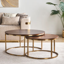 Nest of three round coffee tables with gold metal bases in a living room setting.