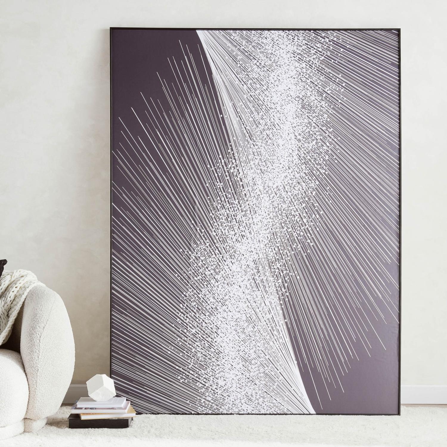 Abstract art piece with white lines on a gray background in a black frame, leaning against a white wall.