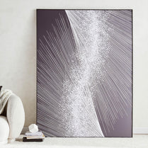 Abstract art piece with white lines on a gray background in a black frame, leaning against a white wall.