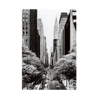 Black and white cityscape with tall buildings and trees lining a street.