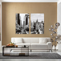 Modern living room with a white sofa, coffee table, and wall art depicting cityscapes.