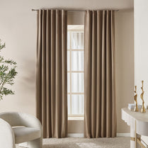 Brown curtains hanging in a room with a chair and decorative items.