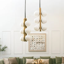 Modern pendant lights hanging above a green sofa with decorative pillows and a framed artwork on the wall.