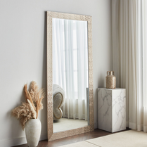 Decorative full-length mirror with a textured frame in a room setting.