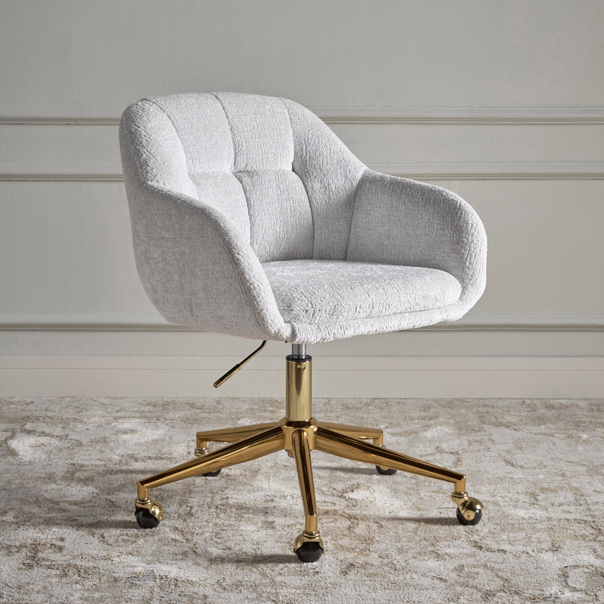Gray upholstered office chair with gold metal base on a neutral background