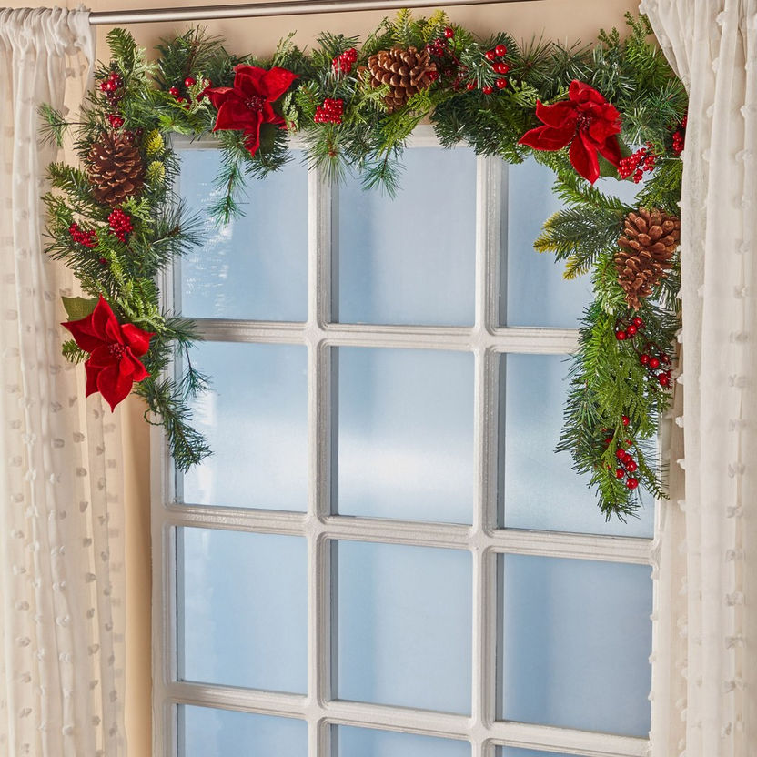 Christmas garland with red bows and pine cones on a window