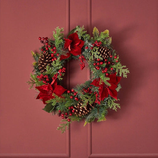 Christmas wreath with red ribbons, berries, and pine cones on a red background