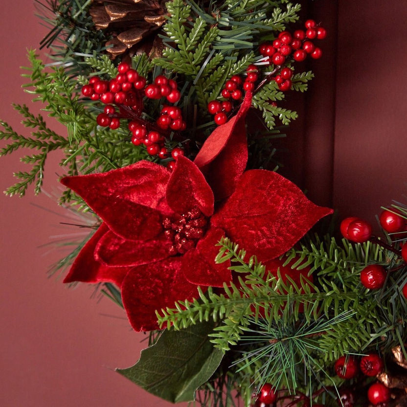 Decorative wreath with red poinsettias and greenery on a red background