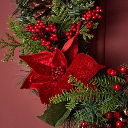 Decorative wreath with red poinsettias and greenery on a red background