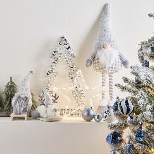 Decorative Christmas scene with gnomes, trees, and ornaments on a white surface.